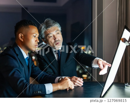 夜のオフィスで画面を見ながら会議する多国籍ビジネスパーソン 夜のオフィスで画面を見ながら会議する多国籍ビジネスパーソン 127069815