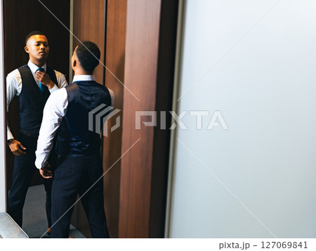 鏡を見て身だしなみを整える外国人男性 鏡を見て身だしなみを整える外国人男性 127069841