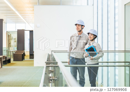 タブレットPCを持ってビルの屋内に立つ男女エンジニア 127069908