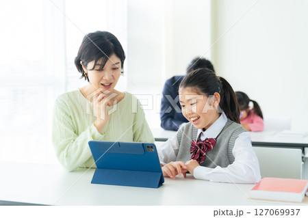女の子にタブレットを使って指導する女性教師 127069937