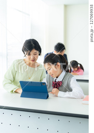 女の子にタブレットを使って指導する女性教師 127069938