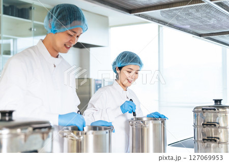 厨房で大鍋で調理する衛生白衣を着た女性調理師 給食センター 給食室 厨房で大鍋で調理する衛生白衣を着た女性調理師 給食センター 給食室 127069953