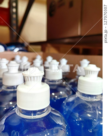 close-up blue liquid bottles stored on shelves in stockroom during daylight hours. 127070307