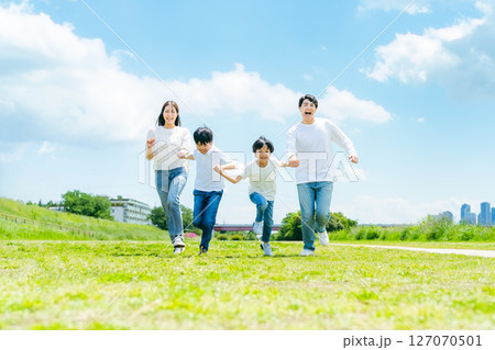 青空の草原を走る家族 127070501