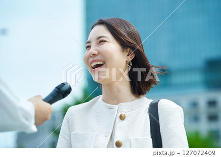 屋外でインタビューを受ける若い女性 127072409