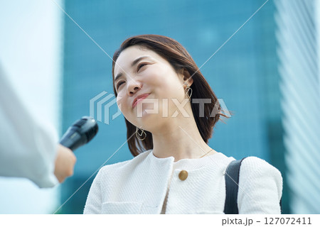 屋外でインタビューを受ける若い女性 127072411