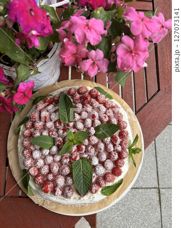 Strawberry pavlova cake decorated with fresh mint leaves and powdered sugar 127073141