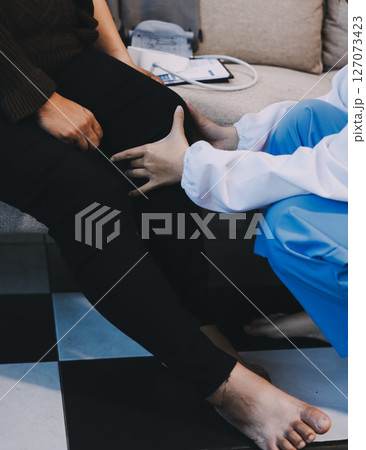 Young doctor examines senior patient's leg Young doctor examines senior patient's leg 127073423
