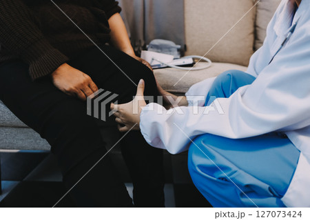 Young doctor examines senior patient's leg Young doctor examines senior patient's leg 127073424