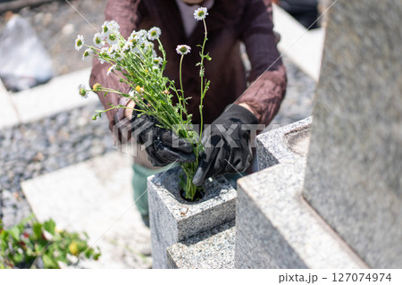 墓前に花を添える女性 127074974