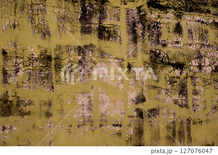 Cracked Yellow Paint with Dark Mold Creating Abstract Texture 127076047