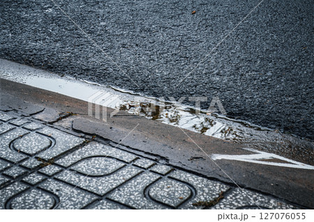 Close-up of a wet sidewalk and asphalt curb after rainfall Close-up of a wet sidewalk and asphalt curb after rainfall 127076055