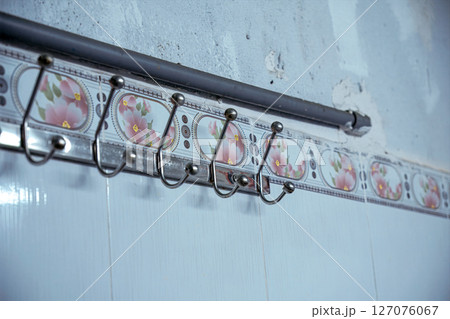 Wall-mounted hooks with floral tiles in a vintage setting 127076067