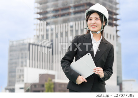 スーツにヘルメット被ってタブレットをもつ若い女性　施工管理者　現場監督　土木女子（ドボジョ） 127077398
