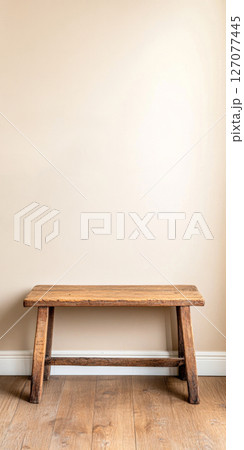 Simple wooden bench against a minimalistic beige wall in a cozy indoor space 127077445