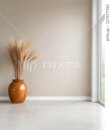 Warm terracotta vase with dried grasses in a bright, modern living room corner 127077492