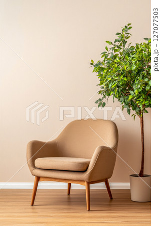 Cozy chair beside a potted plant against a light wall in a modern living space Cozy chair beside a potted plant against a light wall in a modern living space 127077503