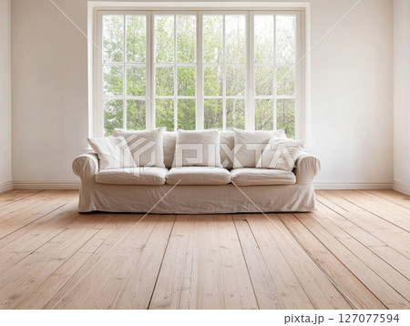 Bright living room with a cozy white sofa and large windows showcasing a green view Bright living room with a cozy white sofa and large windows showcasing a green view 127077594