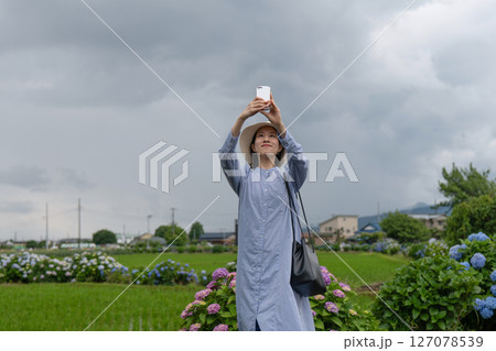 あじさいの咲く6月の里山の田園風景をスマートフォンで撮影する女性 あじさいの咲く6月の里山の田園風景をスマートフォンで撮影する女性 127078539