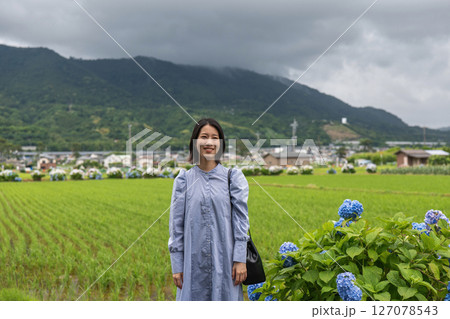 水田と紫陽花を眺めながら里山を歩く女性 水田と紫陽花を眺めながら里山を歩く女性 127078543