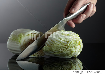 Hand with knife and cut Chinese cabbage. 127078846