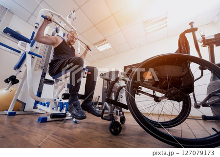 Disabled man doing strength exercises separate from the wheelchair. Disabled man doing strength exercises separate from the wheelchair. 127079173