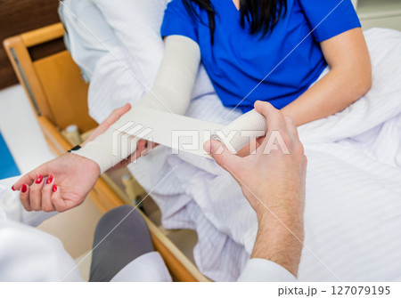 Male doctor bandaging hand of female patients. 127079195