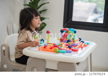 toddler girl playing colorful magnetic construction toy 127079224