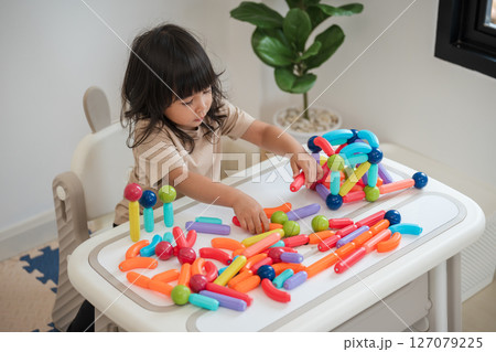 toddler girl playing colorful magnetic construction toy 127079225