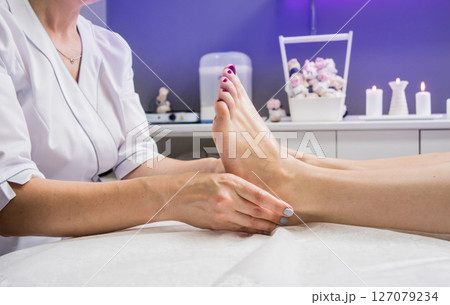 Beautiful young woman enjoying foot massage in spa salon. Cosmetology 127079234