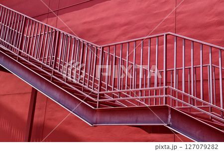 A set of stairs ascending a large red wall A set of stairs ascending a large red wall 127079282