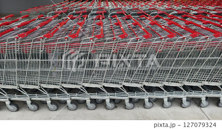 A row of shopping carts is neatly lined up in a straight row 127079324