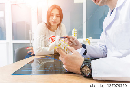Orthopedist showing spine model to patient in hospital 127079350
