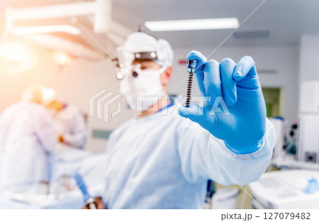 Spinal surgery. Surgeon show polyaxial screw in operating room  127079482