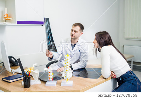 Traumatologist showing MRI film to patient in hospital. Traumatologist showing MRI film to patient in hospital. 127079559