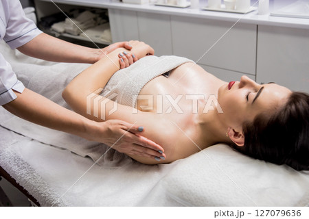 Beautiful young woman enjoying massage in spa salon. Cosmetology 127079636