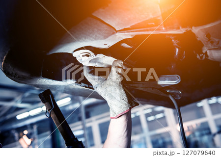 Car mechanic examining car suspension of lifted automobile at service station Car mechanic examining car suspension of lifted automobile at service station 127079640