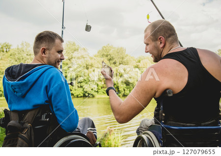 Handicapped men fishing at a lake. Wheelchair. Camping. 127079655