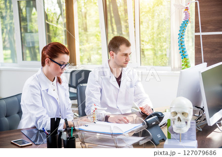 Two doctors having medical council in hospital. Discussing medical issues. Two doctors having medical council in hospital. Discussing medical issues. 127079686