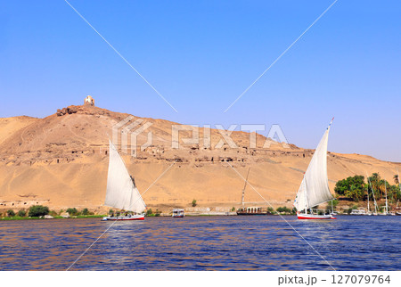 Traditional sailing boat felucca, Nile river near Aswan, Egypt. A famous tourist attraction - sailing boat ride. Topic of vacation, travel, trip abroad on vacation, cruises and tours 127079764
