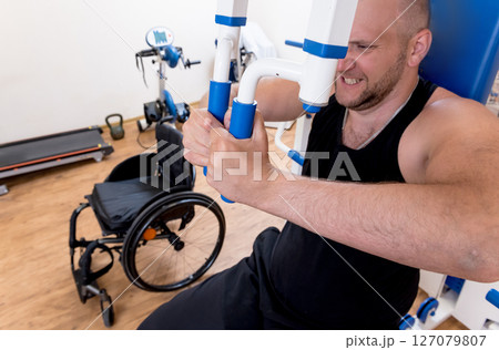 Disabled man doing strength exercises separate from the wheelchair. Disabled man doing strength exercises separate from the wheelchair. 127079807