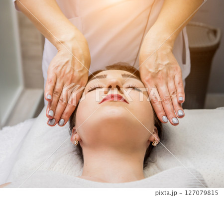 Beautiful young woman enjoying head massage in spa salon. Cosmetology Beautiful young woman enjoying head massage in spa salon. Cosmetology 127079815