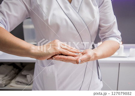 Masseur putting aroma oil on her hands, preparing for massage in spa center Masseur putting aroma oil on her hands, preparing for massage in spa center 127079882
