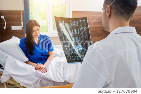 Traumatologist showing MRI film to patient in hospital. 127079904