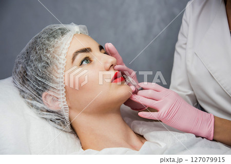 The doctor cosmetologist makes the facial injections procedure. Young woman The doctor cosmetologist makes the facial injections procedure. Young woman 127079915