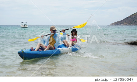 The young couple are happily navigating together in a light blue kayak with yellow paddles 127080047
