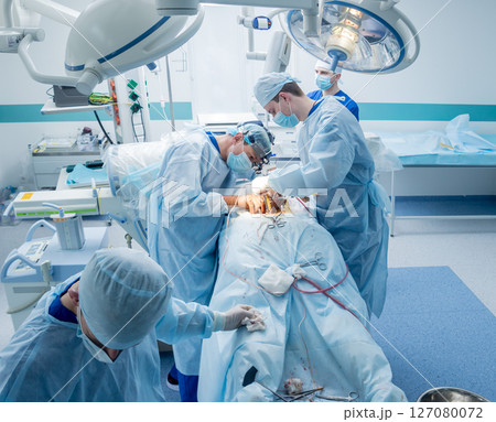 Spinal surgery. Group of surgeons in operating room with surgery equipment.  127080072