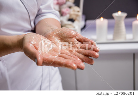 Masseur putting aroma oil on her hands, preparing for massage in spa center 127080201