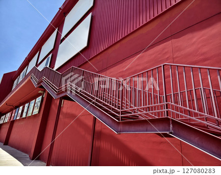 A set of stairs ascending a large red wall 127080283