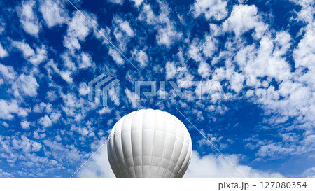 White hot air balloon against vibrant blue cloudy sky 127080354